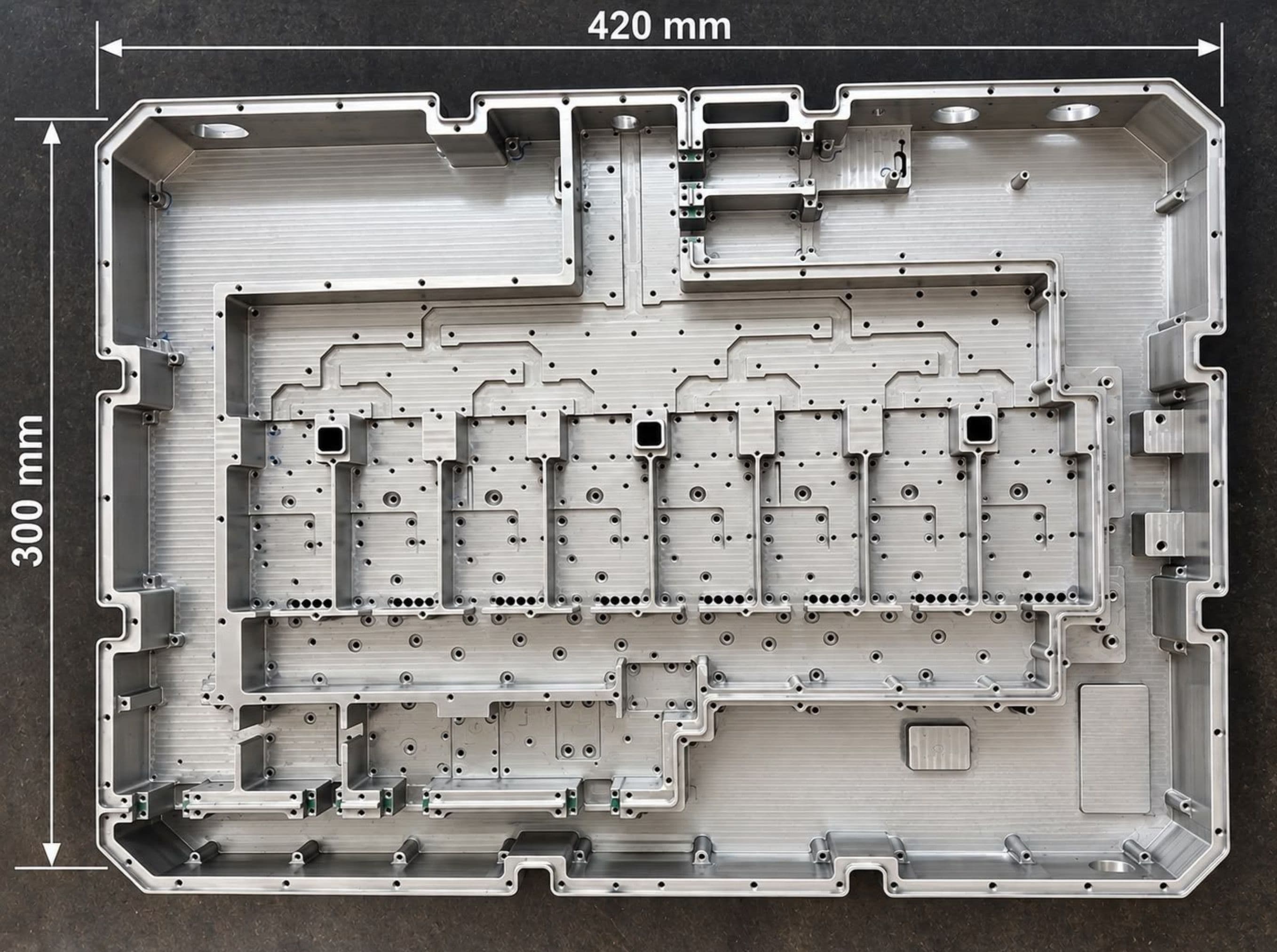 Machined housing with internal compartments and many tapped holes, annotated with overall dimensions of 300 mm by 420 mm.