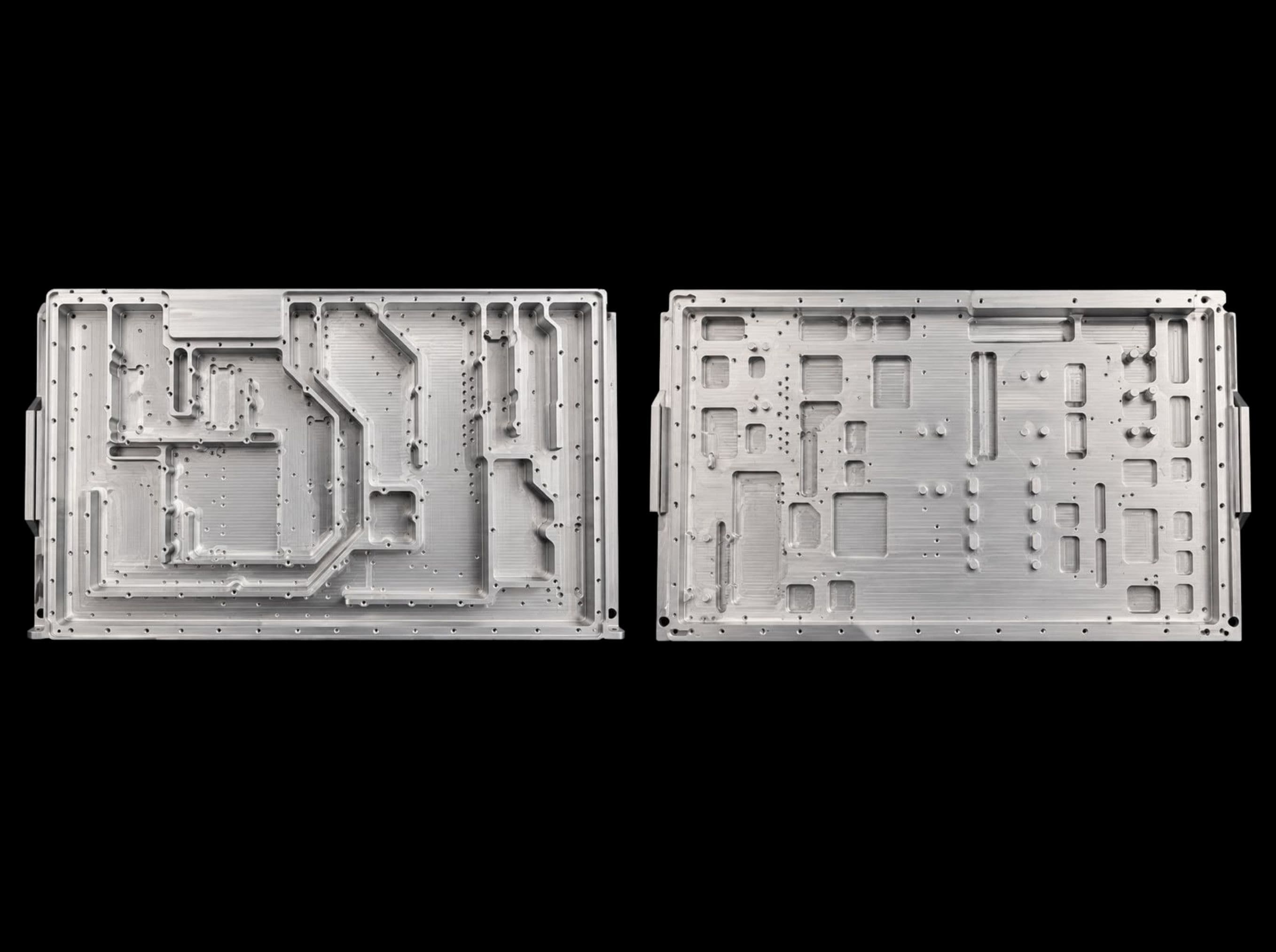 Two flat plates side by side, machined with raised walls, pockets and rows of drilled holes.